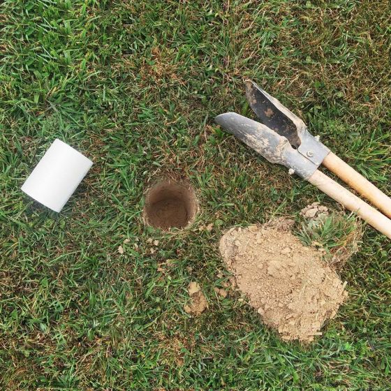 Digging a hole in the ground for the Tour Gear Portable Golf flag's cup